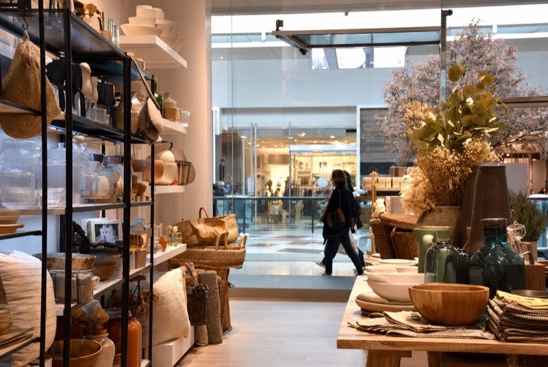 A brightly lit shop interior with neat shelves of home goods and gifts
